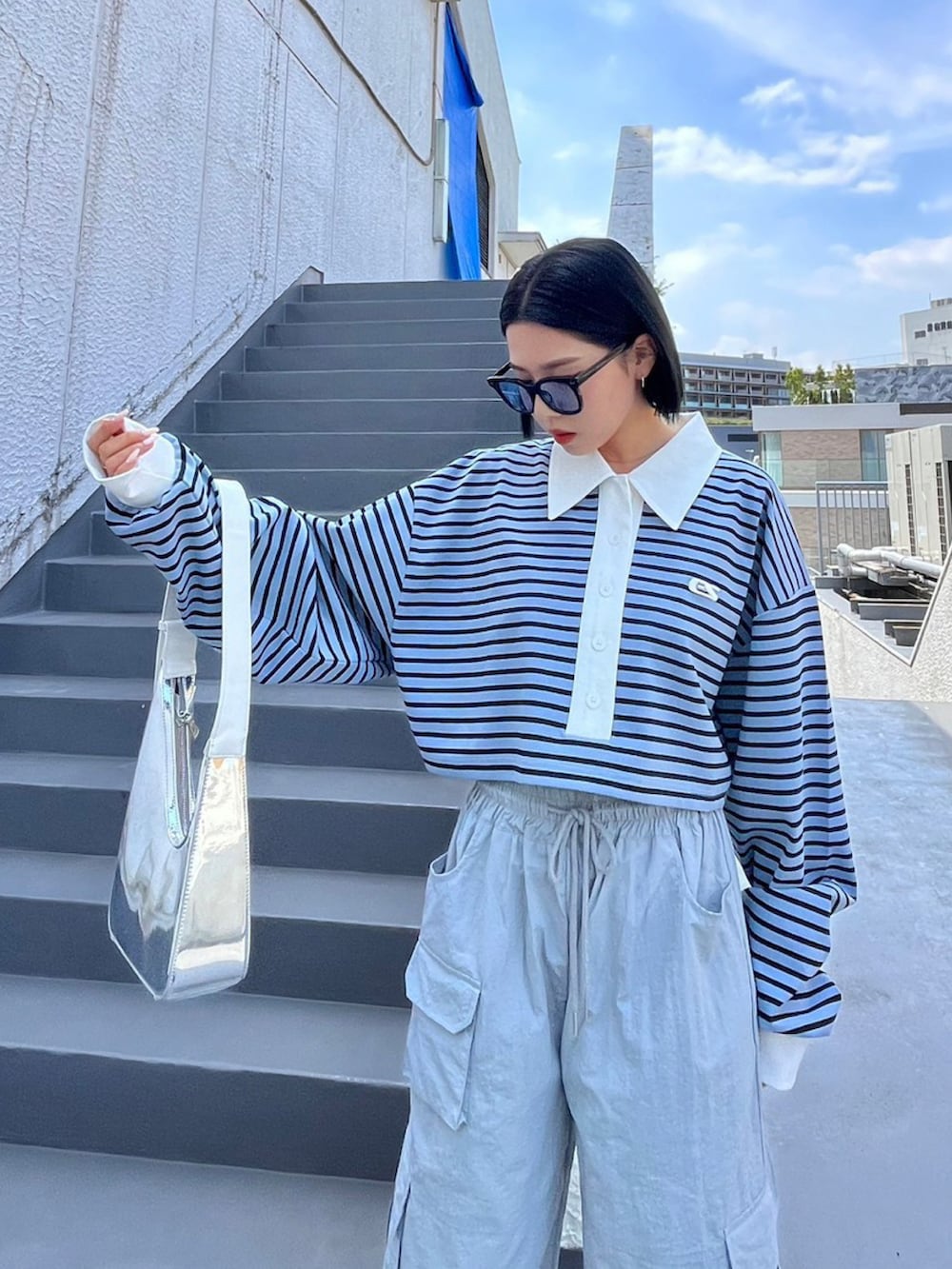 ブルー系のポロシャツ、ブルー系のサングラスを着用したレディースの夏コーディネートの2枚目の写真