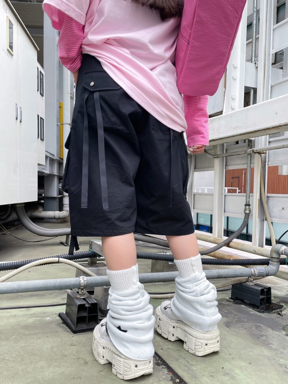 ピンク系のハンドバッグ、ブラック系のカーゴパンツ、ホワイト系のレッグウォーマーを着用したレディースの春コーディネートの3枚目の写真