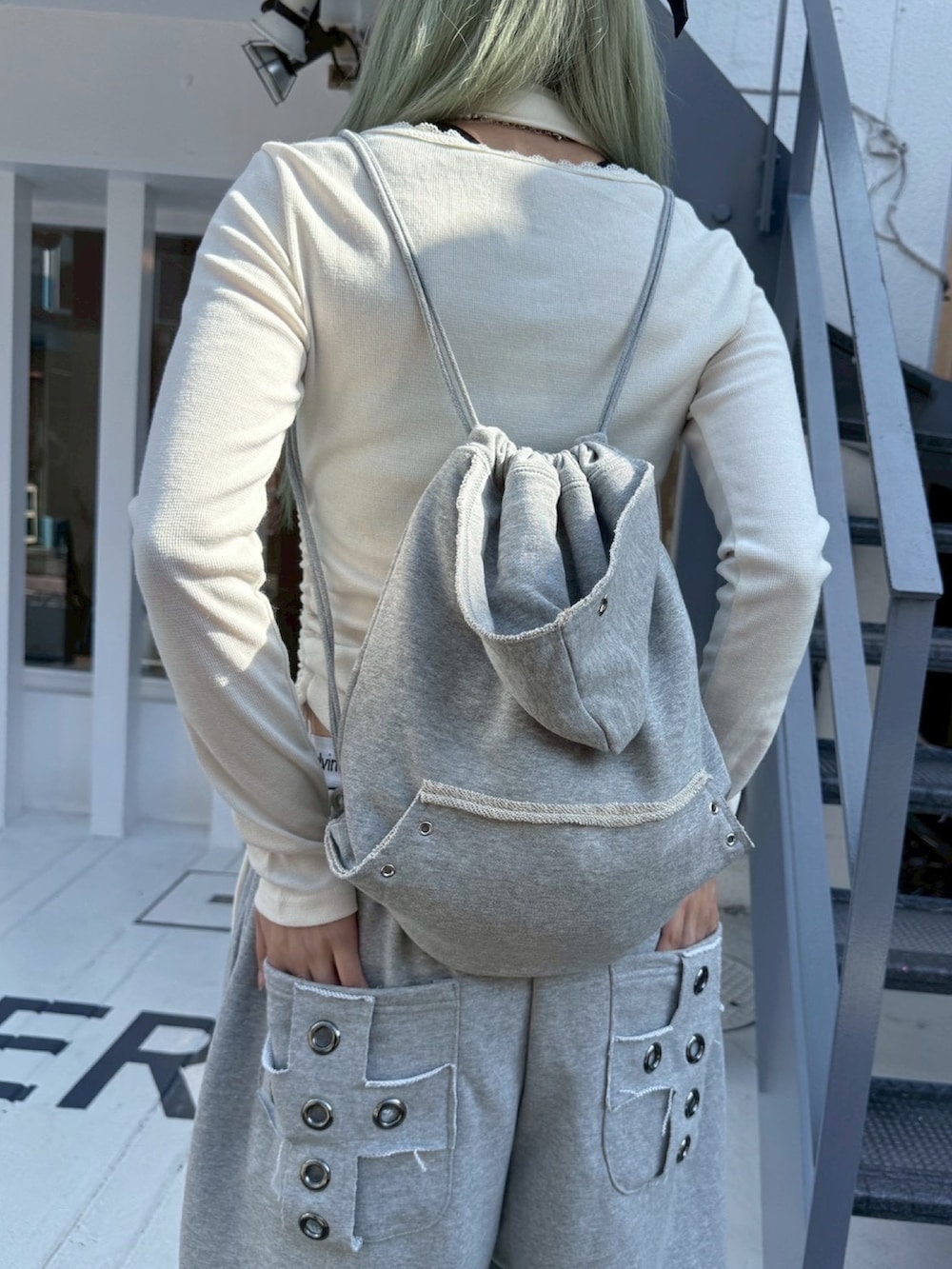 ホワイト系のTシャツ/カットソー、グレー系のスウェットパンツ、グレー系のバックパック/リュックを着用したレディースの冬コーディネートの5枚目の写真