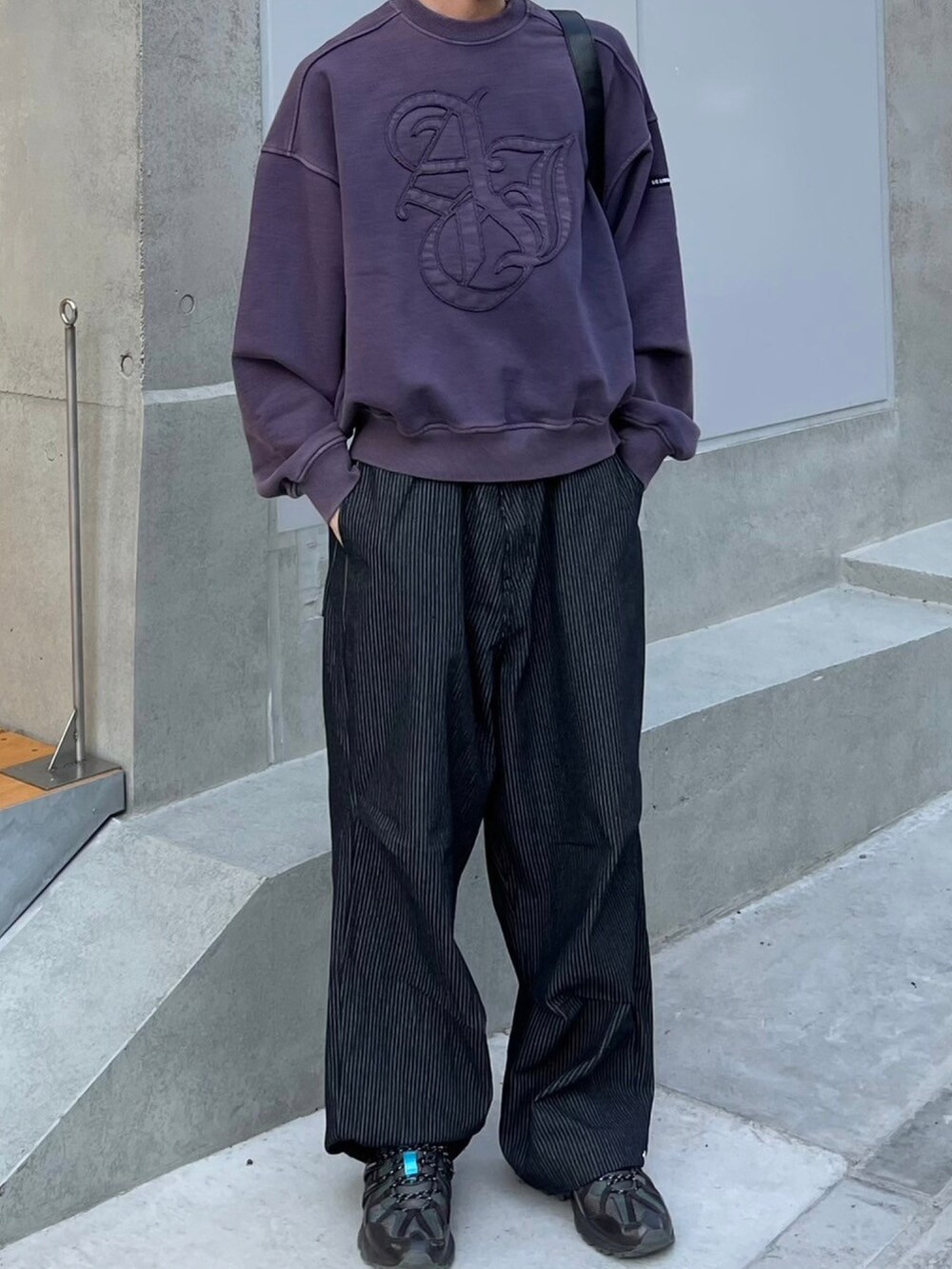 ブラック系のショルダーバッグ、ブラック系のデニムパンツ、パープル系のスウェットを着用したメンズの春コーディネートの3枚目の写真