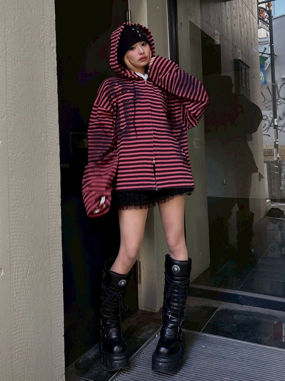 レッド系のパーカー、ブラック系のニットキャップ/ビーニーを着用したレディースの春コーディネートの2枚目の写真