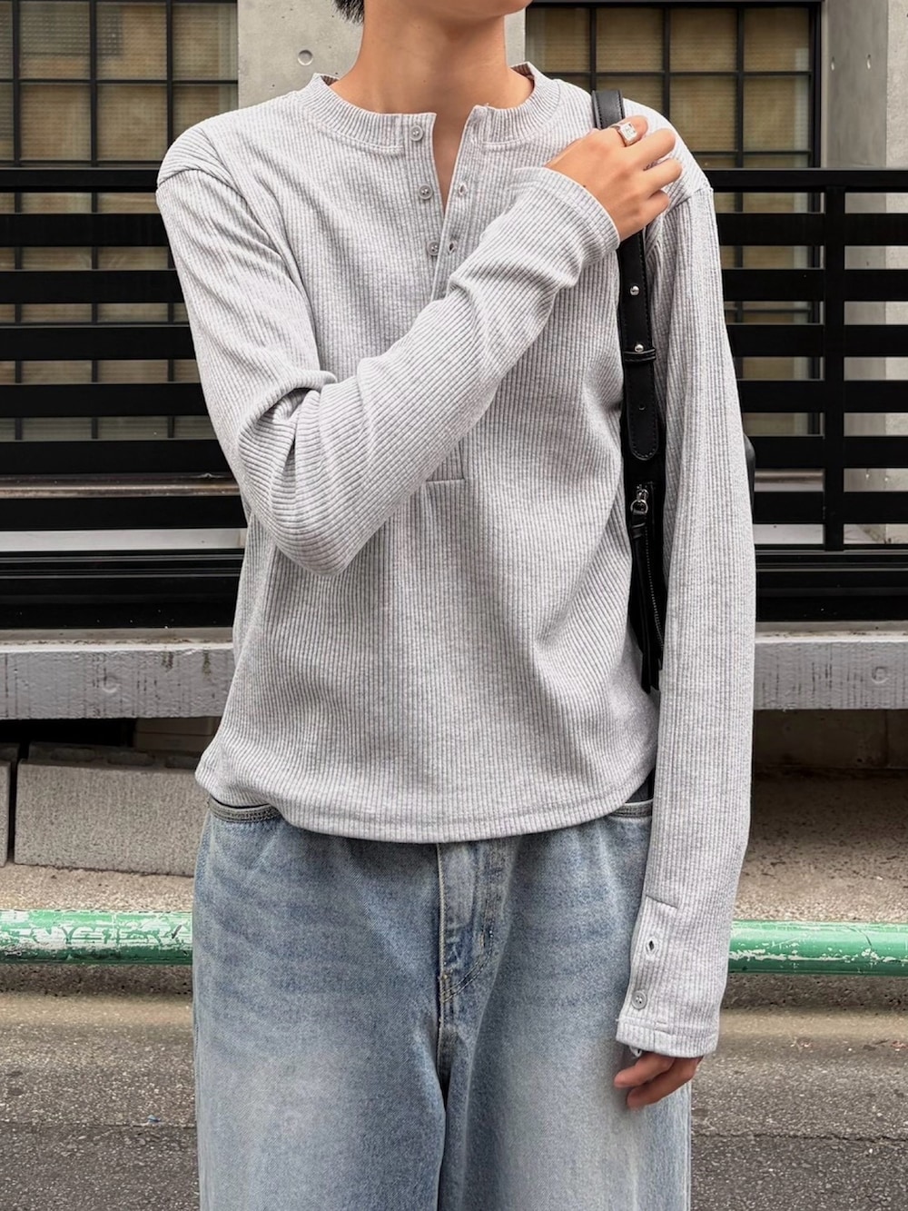 グレー系のTシャツ/カットソー、ブラック系のショルダーバッグ、ブルー系のデニムパンツを着用したメンズの秋コーディネートの5枚目の写真
