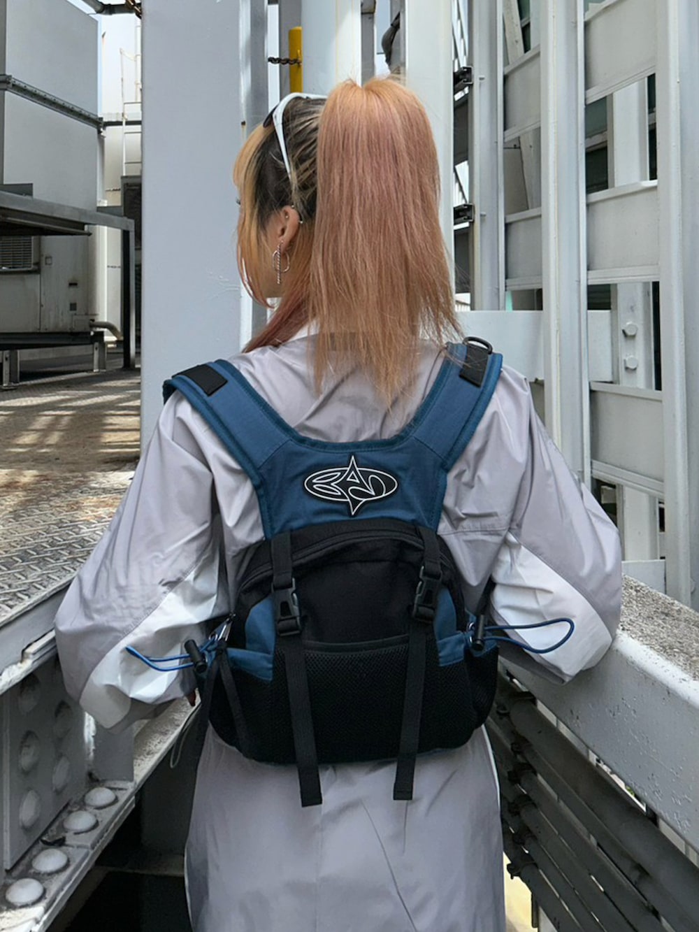 グレー系のセットアップ、ブルー系のバックパック/リュック、ホワイト系のレッグウォーマーを着用したレディースの秋コーディネートの3枚目の写真