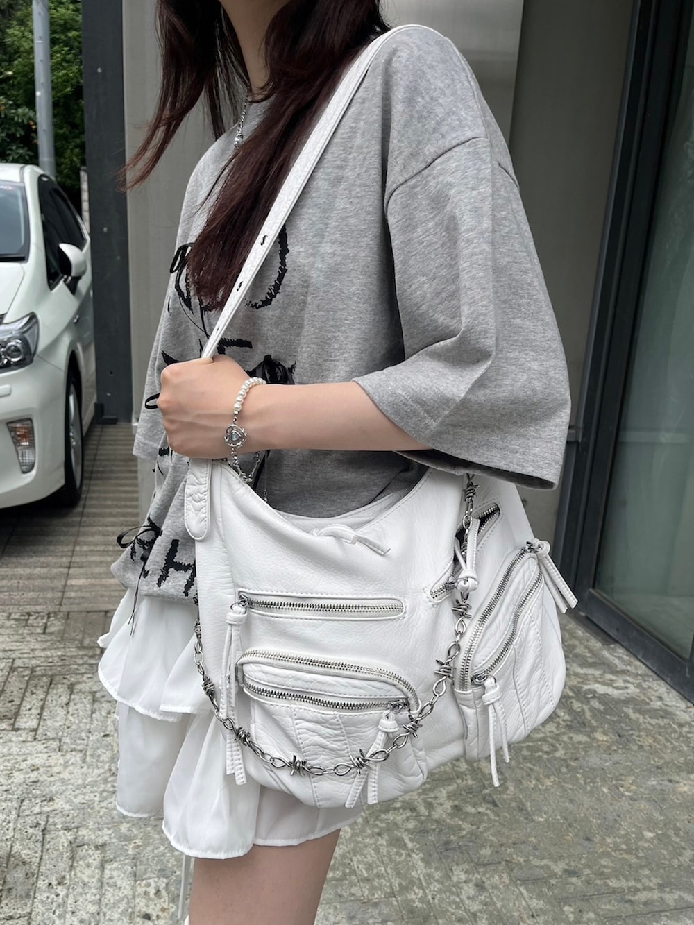 ホワイト系のショルダーバッグ、ホワイト系のキャップ、シルバー系のネックレスを着用したレディースの春コーディネートの3枚目の写真