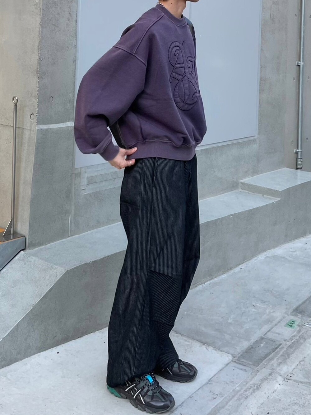 ブラック系のショルダーバッグ、ブラック系のデニムパンツ、パープル系のスウェットを着用したメンズの春コーディネートの2枚目の写真