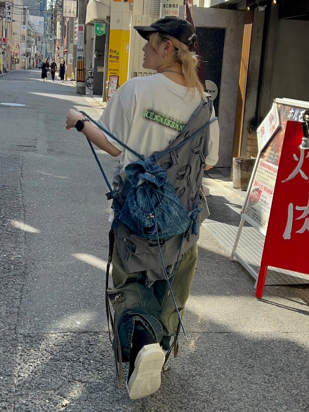 グレー系のパーカー、ブルー系のデニムパンツ、ブラック系のスニーカーを着用したレディースの春コーディネートの4枚目の写真