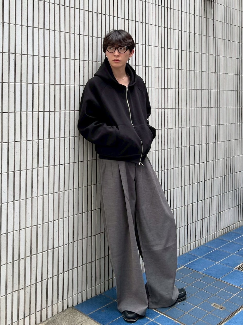 ブラック系のパーカー、グレー系のスラックスを着用したメンズの冬コーディネートの2枚目の写真