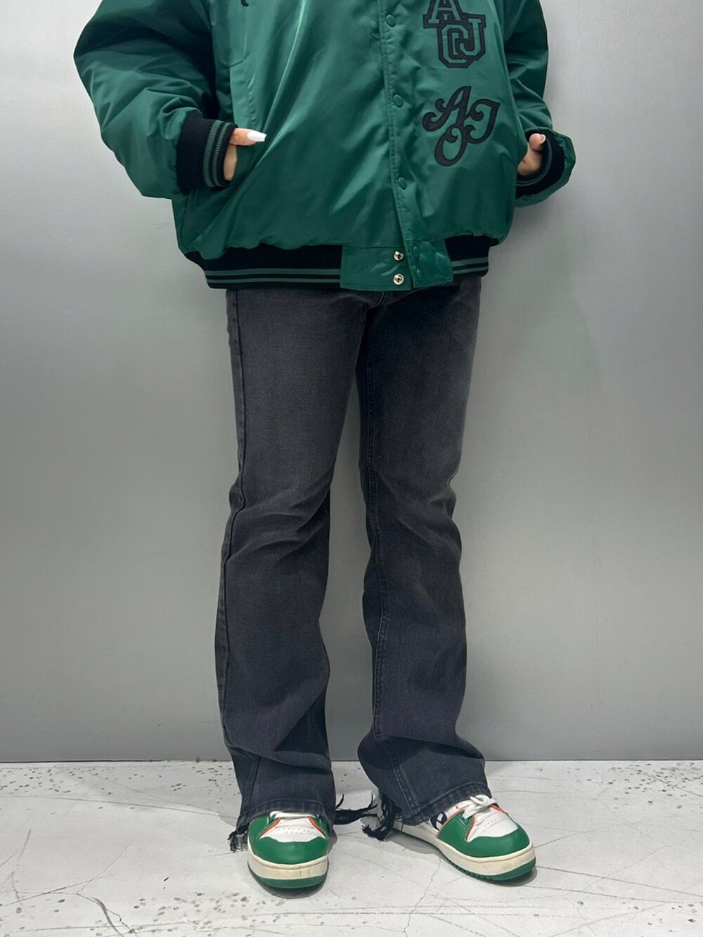 グリーン系のスカジャン、ブラック系のデニムパンツを着用したレディースの秋コーディネートの4枚目の写真