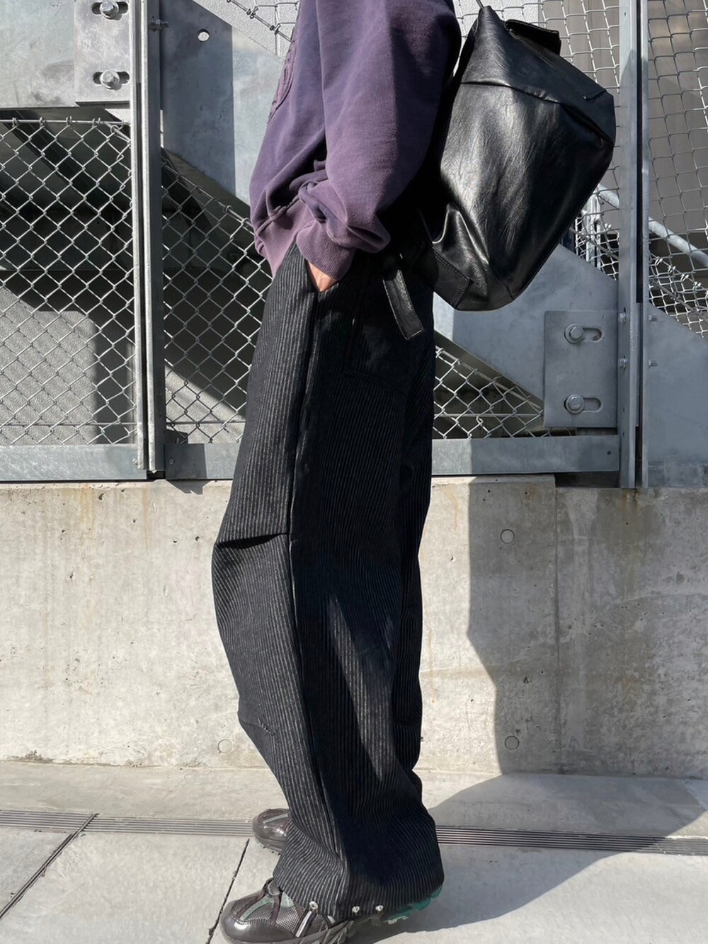 ブラック系のショルダーバッグ、ブラック系のデニムパンツ、パープル系のスウェットを着用したメンズの春コーディネートの4枚目の写真