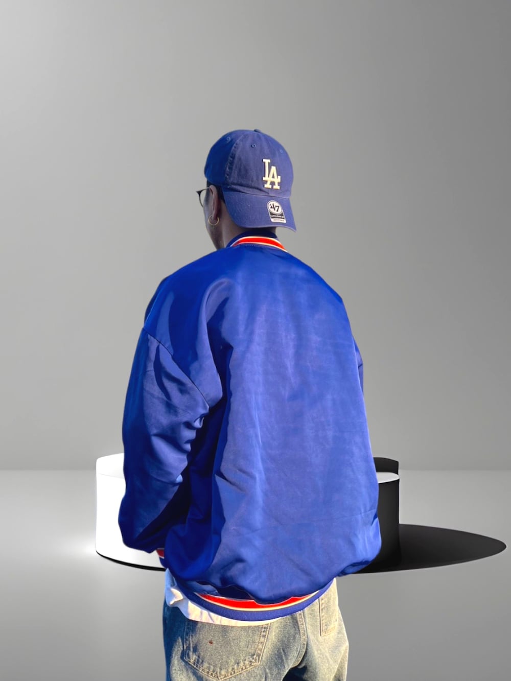 ブルー系のスタジャン、ブルー系のデニムパンツ、ホワイト系のスニーカーを着用したメンズの春コーディネートの2枚目の写真