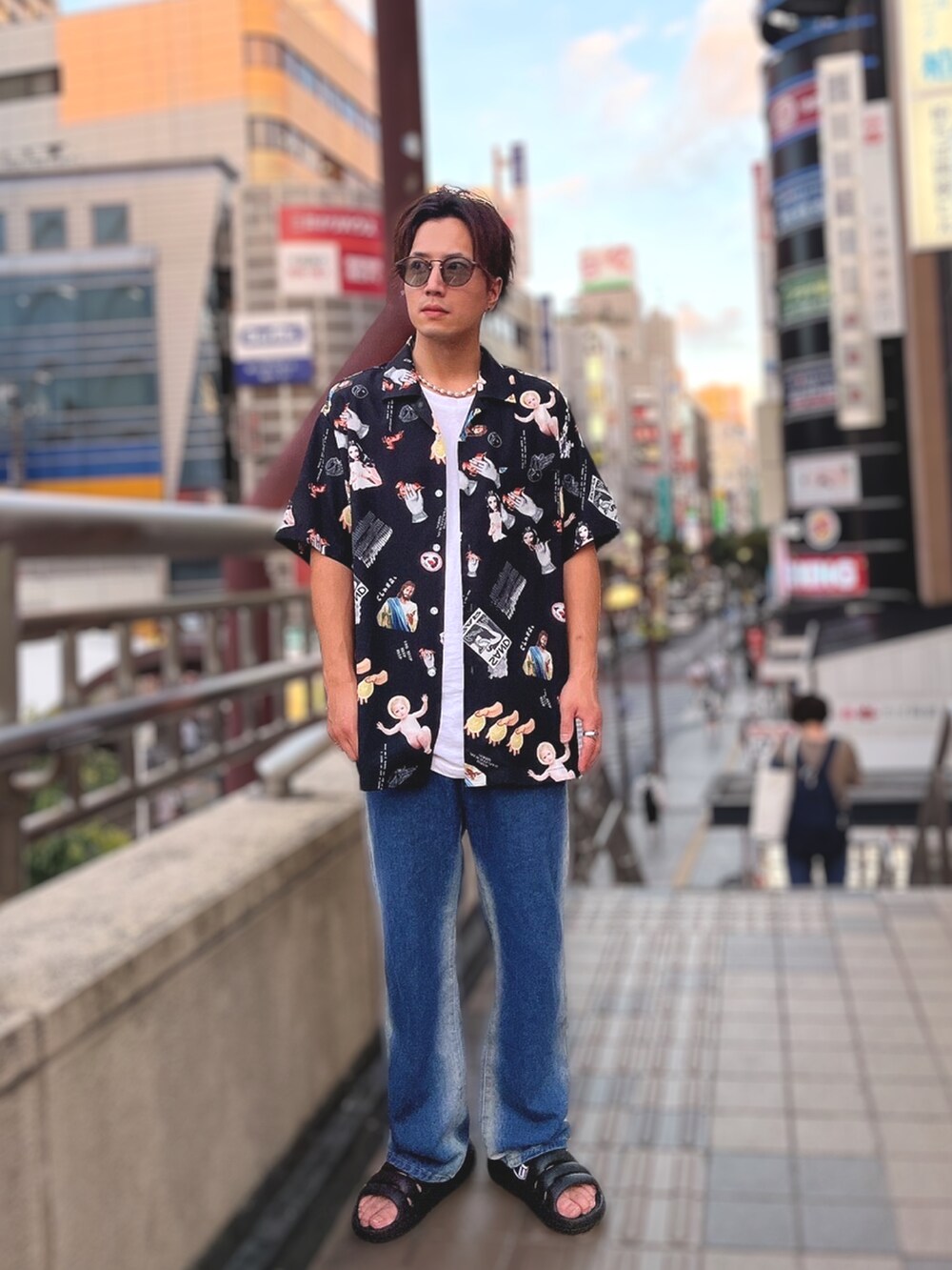 ブラック系のサンダル、ブルー系のデニムパンツ、グリーン系のショルダーバッグを着用したメンズの夏コーディネートの2枚目の写真