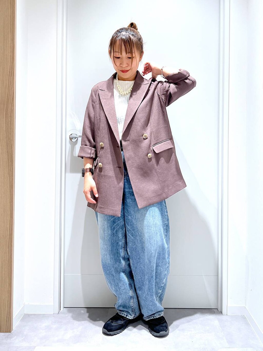 ブルー系のデニムパンツ、ブラウン系のテーラードジャケット、ブラック系のスニーカーを着用したレディースの春コーディネートの5枚目の写真