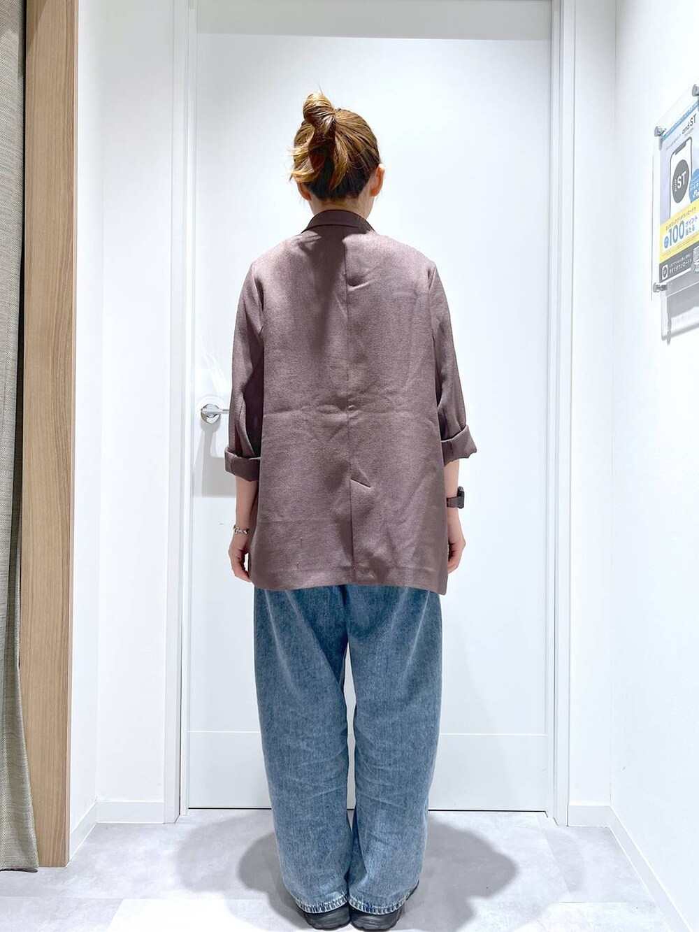 ブルー系のデニムパンツ、ブラウン系のテーラードジャケット、ブラック系のスニーカーを着用したレディースの春コーディネートの3枚目の写真