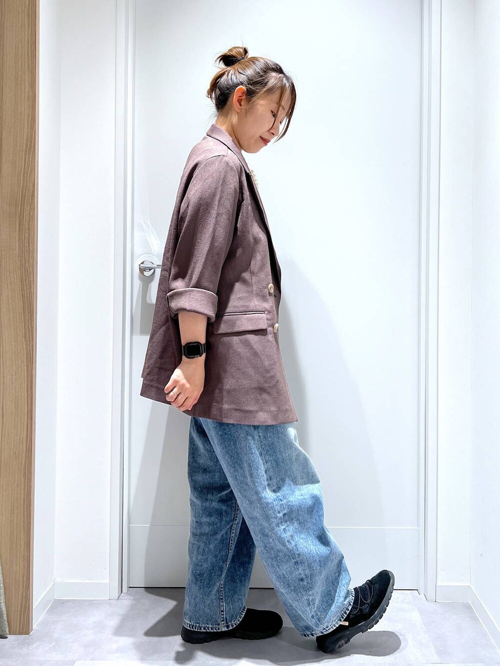 ブルー系のデニムパンツ、ブラウン系のテーラードジャケット、ブラック系のスニーカーを着用したレディースの春コーディネートの2枚目の写真