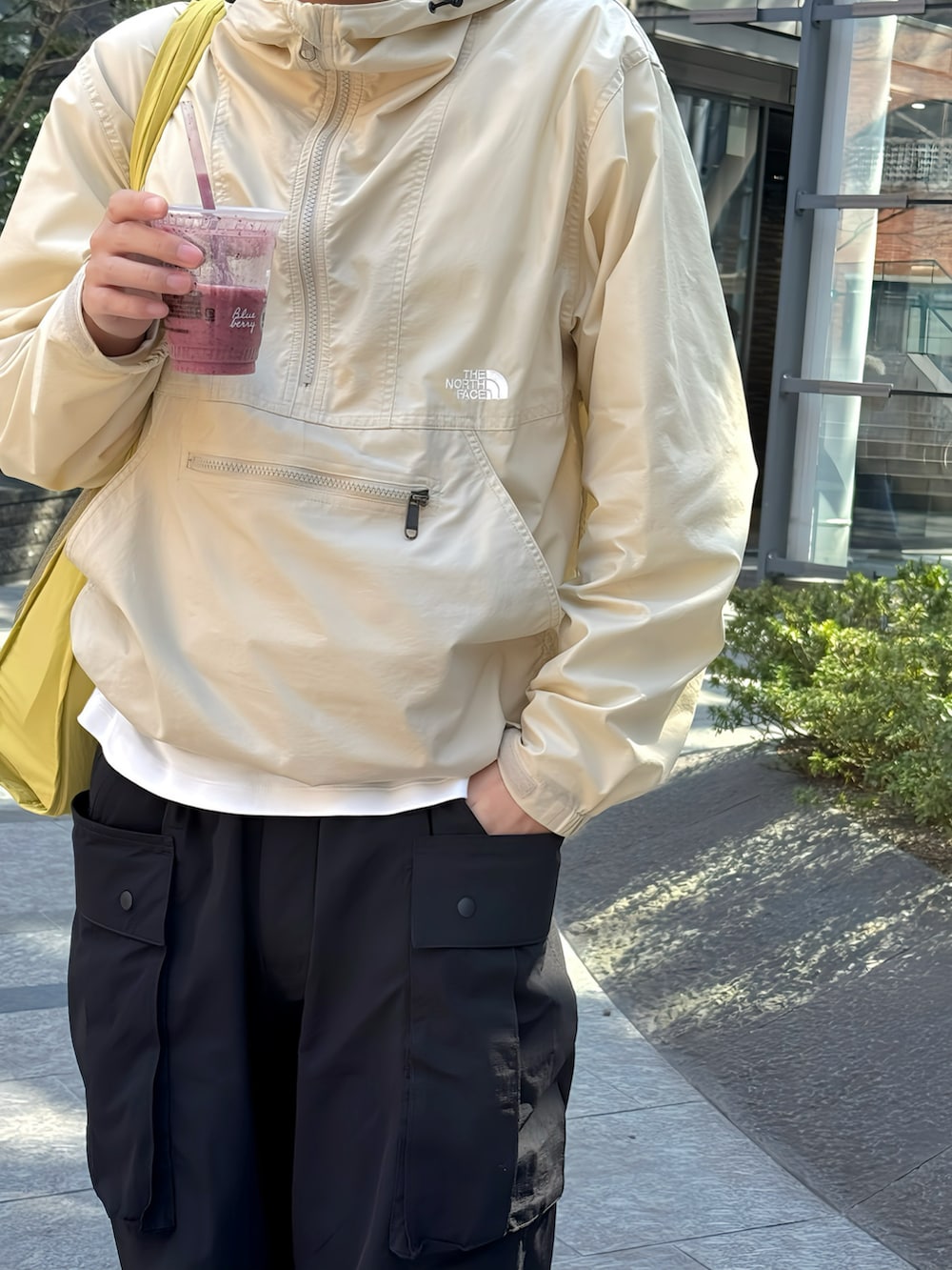 ベージュ系のナイロンジャケット、ブラック系のカーゴパンツ、ホワイト系のスニーカーを着用したメンズの春コーディネートの2枚目の写真