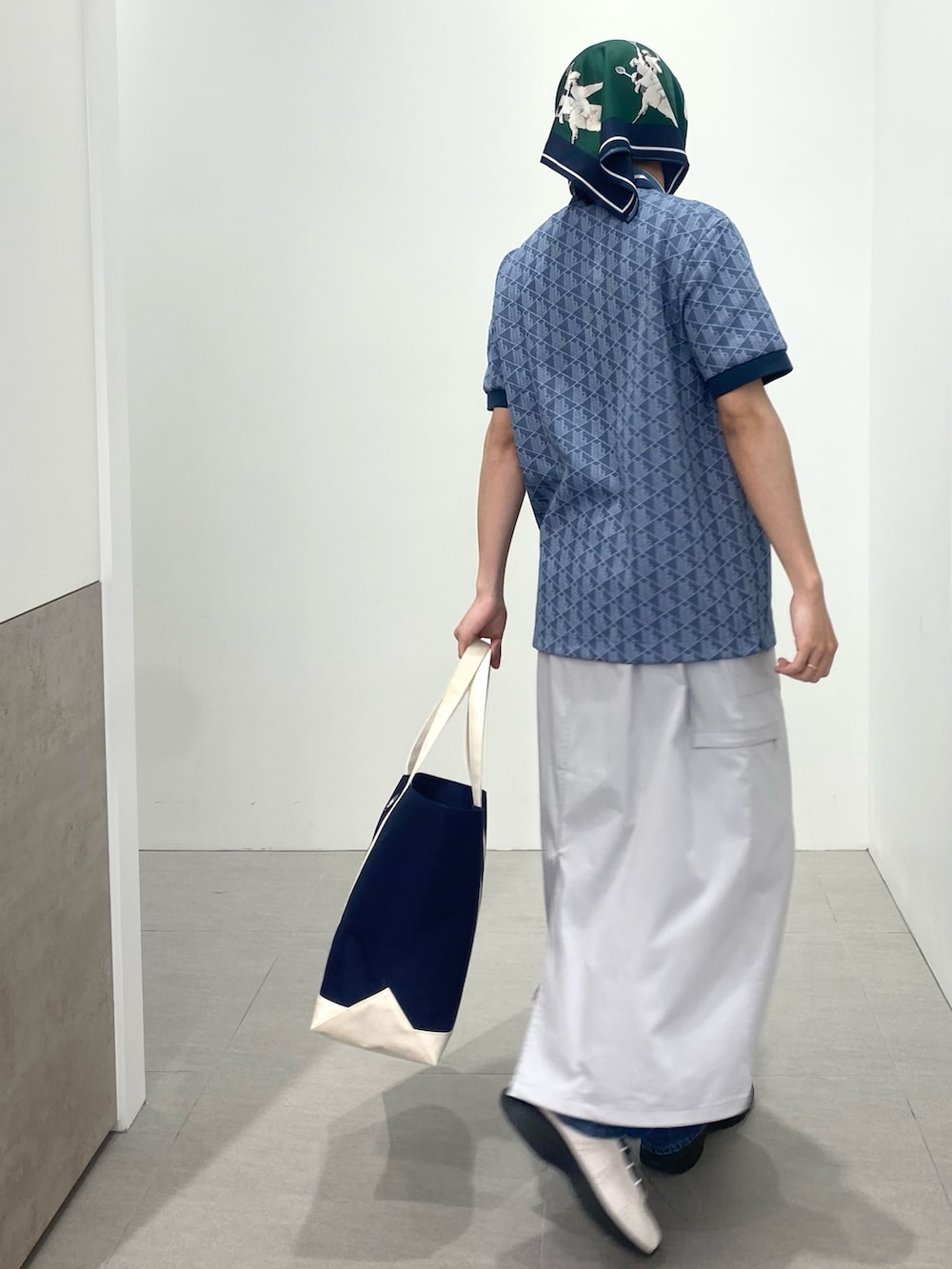 ブルー系のポロシャツ、ホワイト系のスニーカー、ブルー系のトートバッグを着用したメンズの春コーディネートの2枚目の写真