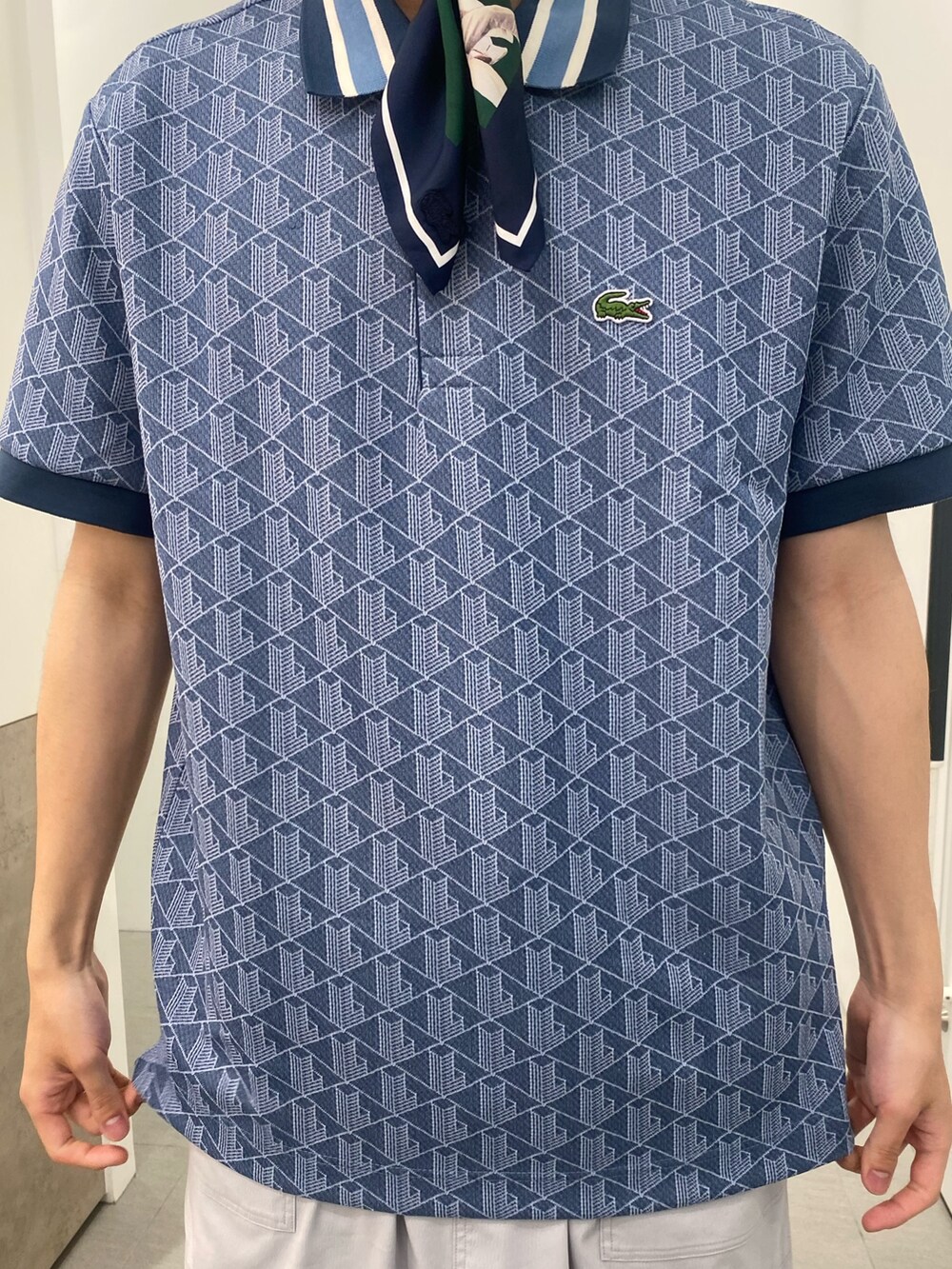 ブルー系のポロシャツ、ホワイト系のスニーカー、ブルー系のトートバッグを着用したメンズの春コーディネートの9枚目の写真