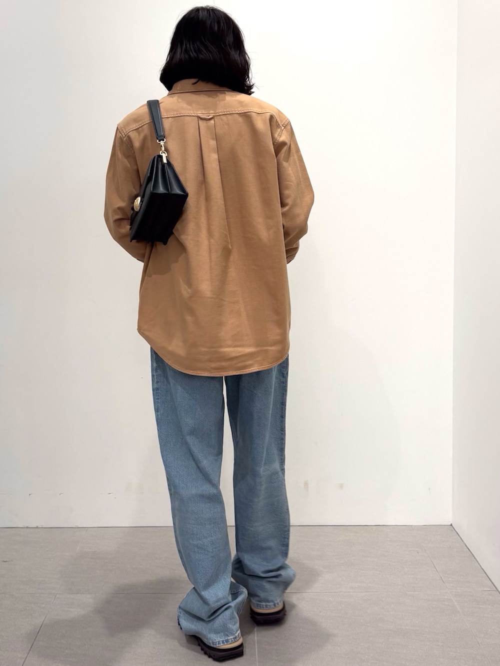 ブラック系のダウンジャケット/コート、イエロー系のシャツ/ブラウス、ブルー系のデニムパンツを着用したメンズの秋コーディネートの4枚目の写真