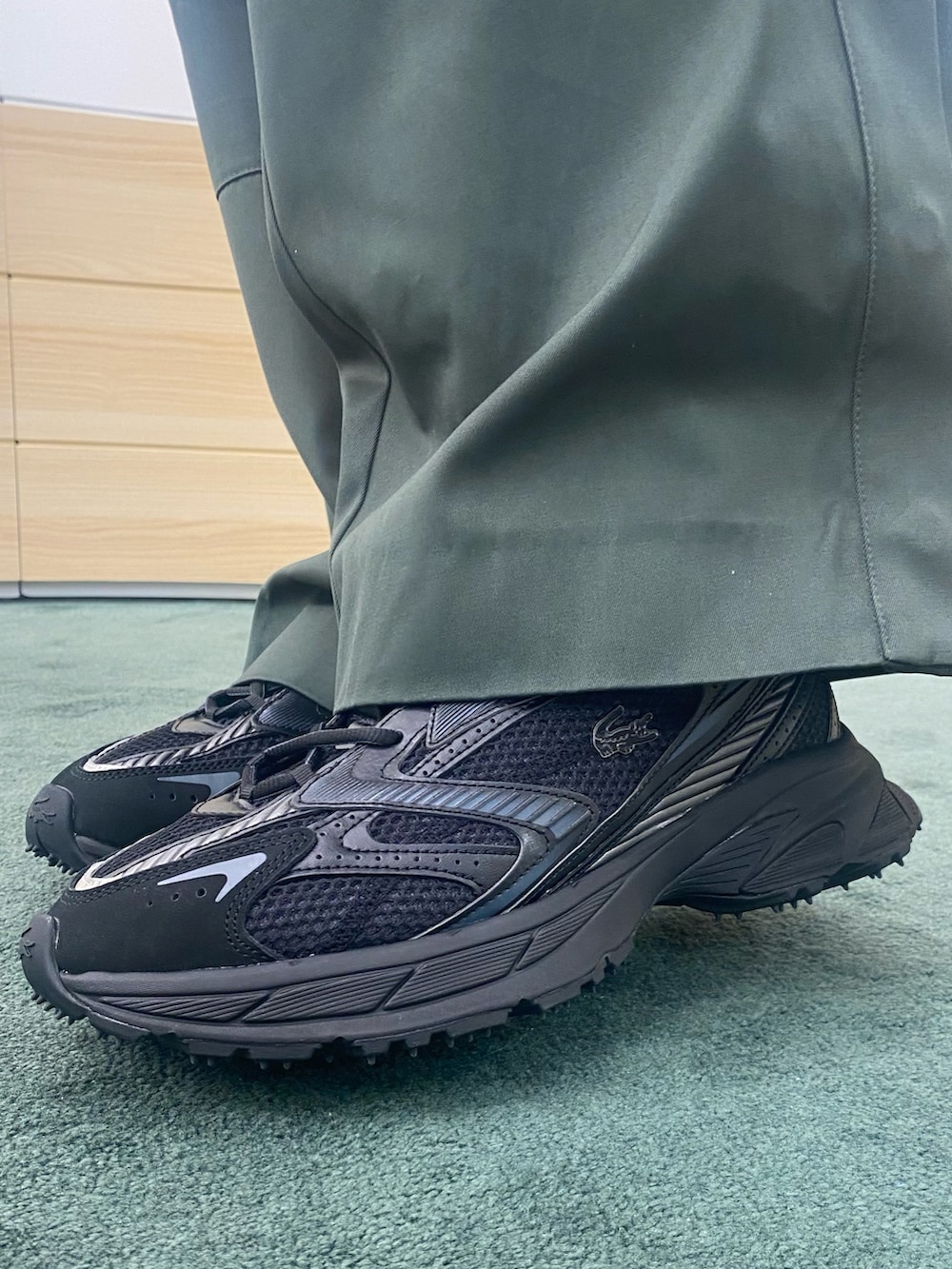 グリーン系のポロシャツ、ブラック系のショルダーバッグ、ホワイト系のベストを着用したメンズの春コーディネートの7枚目の写真