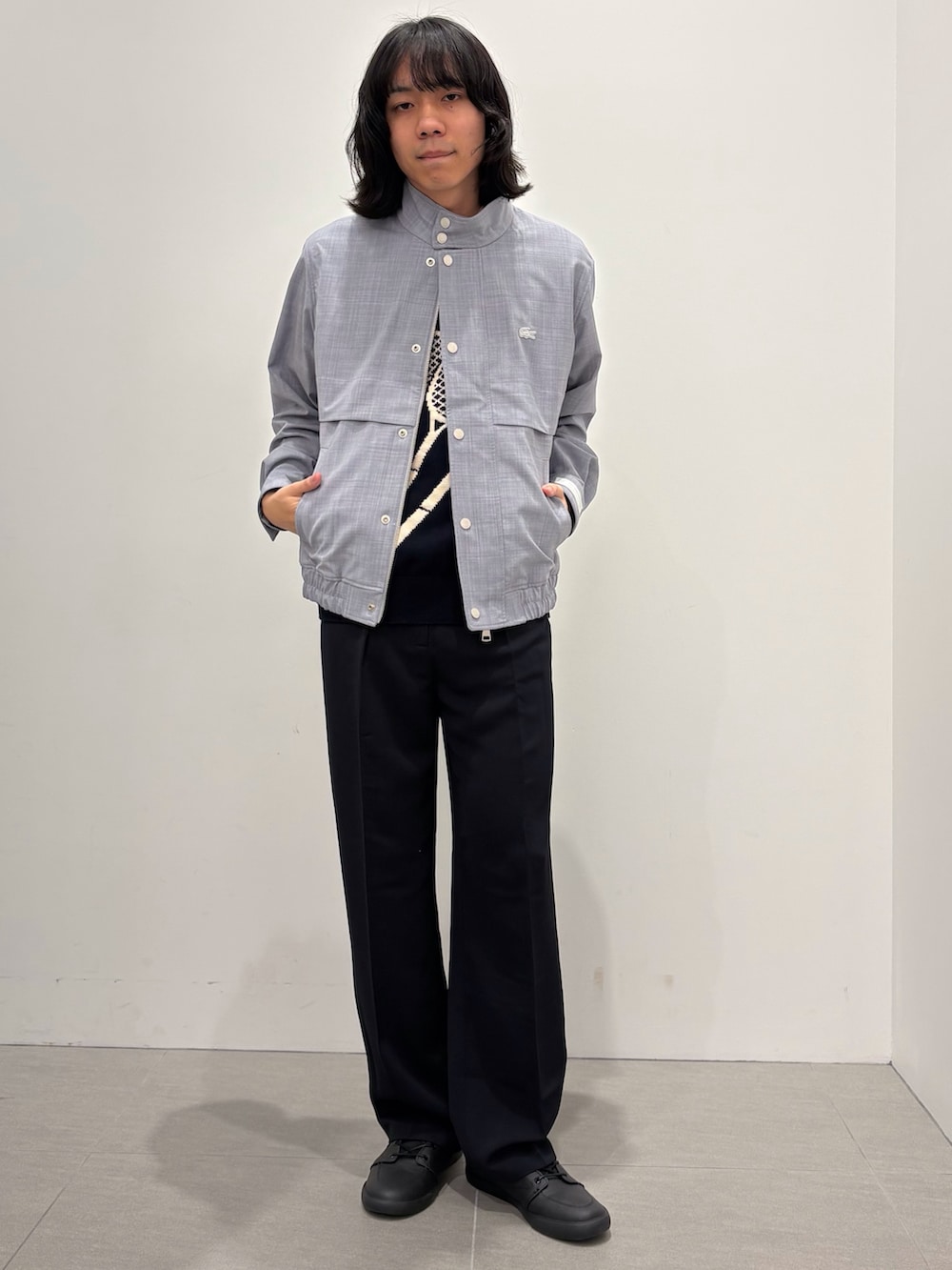 ブラック系のベスト、ブルー系のスラックス、ブラック系のスニーカーを着用したメンズの春コーディネートの2枚目の写真