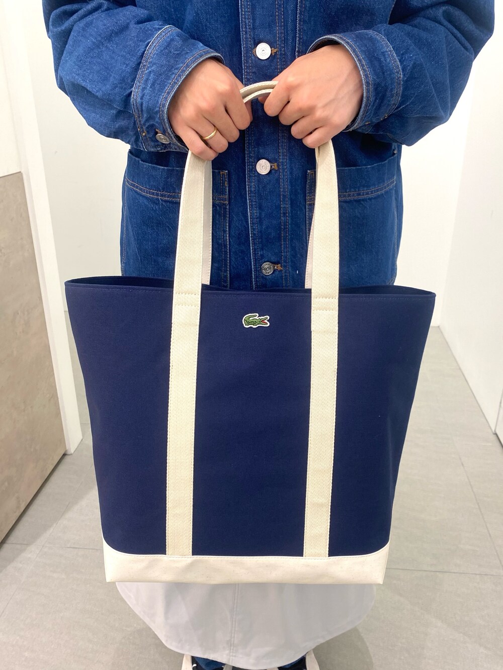 ブルー系のポロシャツ、ホワイト系のスニーカー、ブルー系のトートバッグを着用したメンズの春コーディネートの7枚目の写真