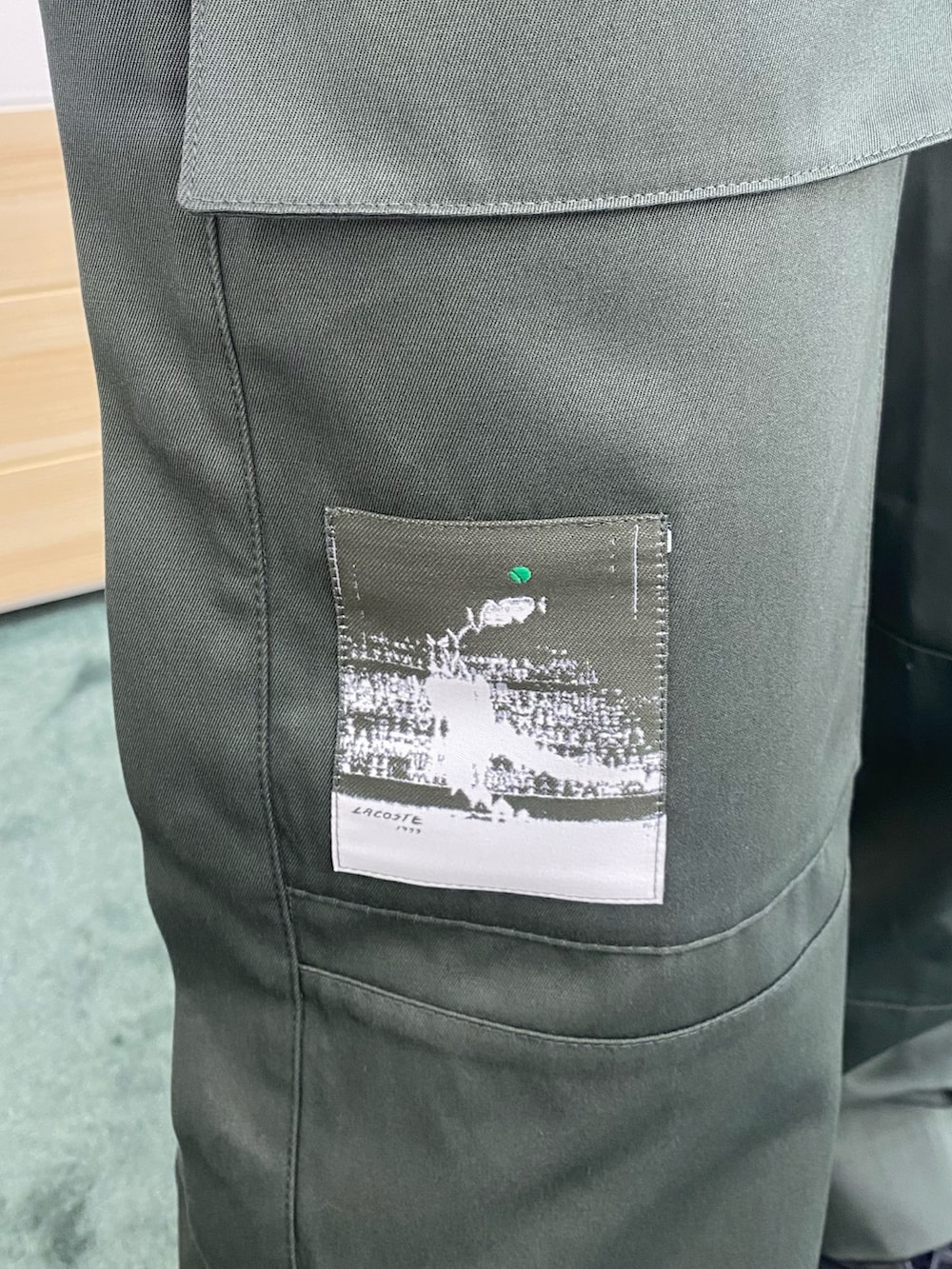 グリーン系のポロシャツ、ブラック系のショルダーバッグ、ホワイト系のベストを着用したメンズの春コーディネートの6枚目の写真