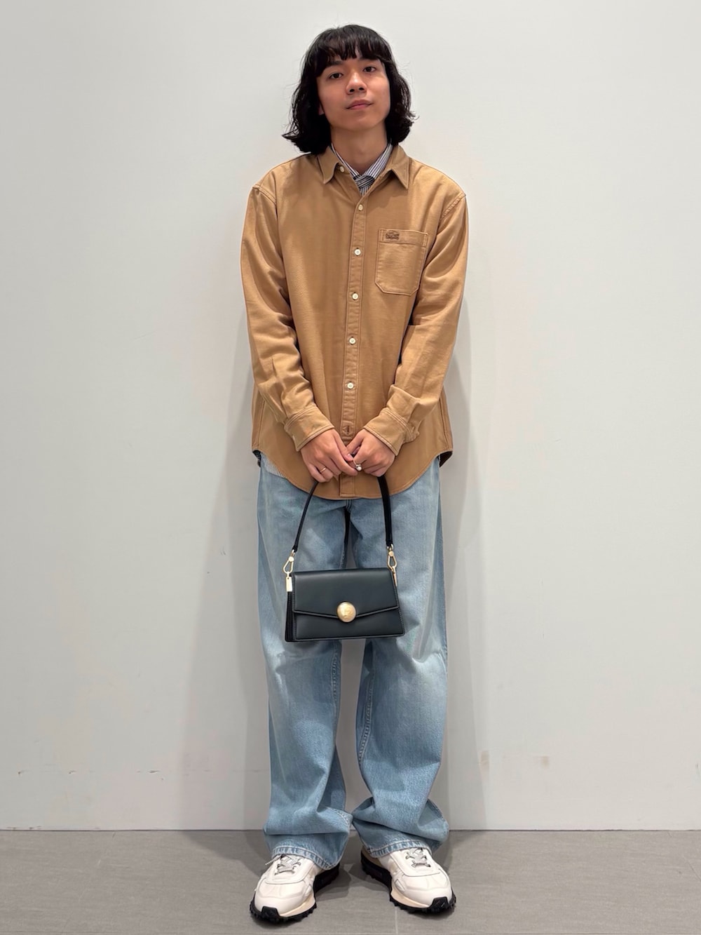 ブラック系のダウンジャケット/コート、イエロー系のシャツ/ブラウス、ブルー系のデニムパンツを着用したメンズの秋コーディネートの3枚目の写真