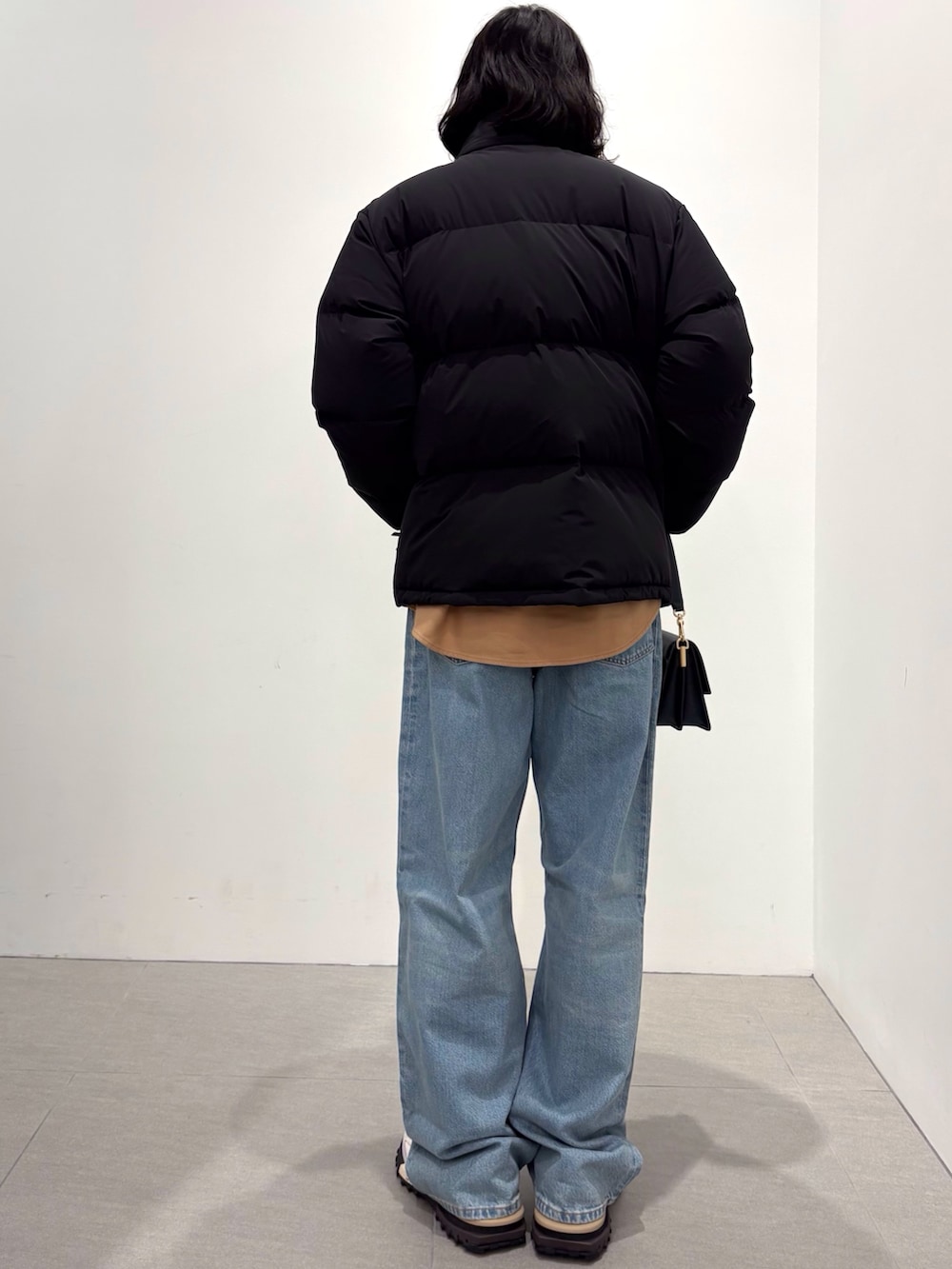 ブラック系のダウンジャケット/コート、イエロー系のシャツ/ブラウス、ブルー系のデニムパンツを着用したメンズの秋コーディネートの2枚目の写真