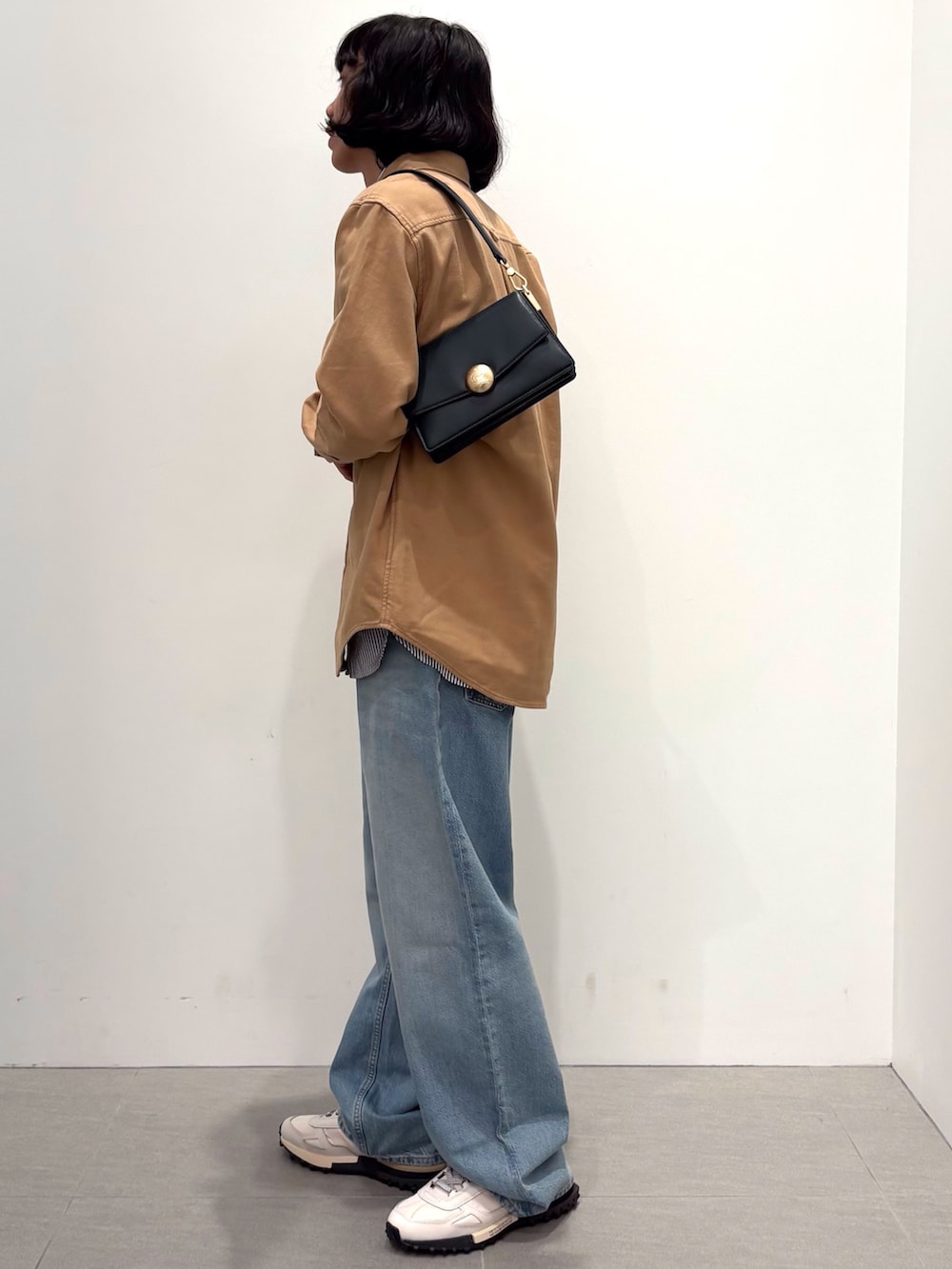 ブラック系のダウンジャケット/コート、イエロー系のシャツ/ブラウス、ブルー系のデニムパンツを着用したメンズの秋コーディネートの5枚目の写真