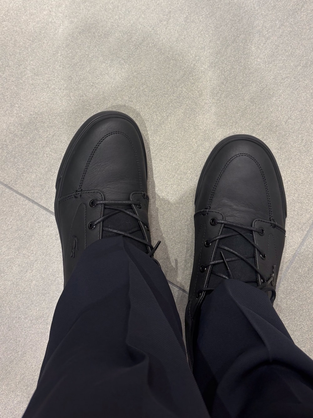 ブラック系のベスト、ブルー系のスラックス、ブラック系のスニーカーを着用したメンズの春コーディネートの5枚目の写真