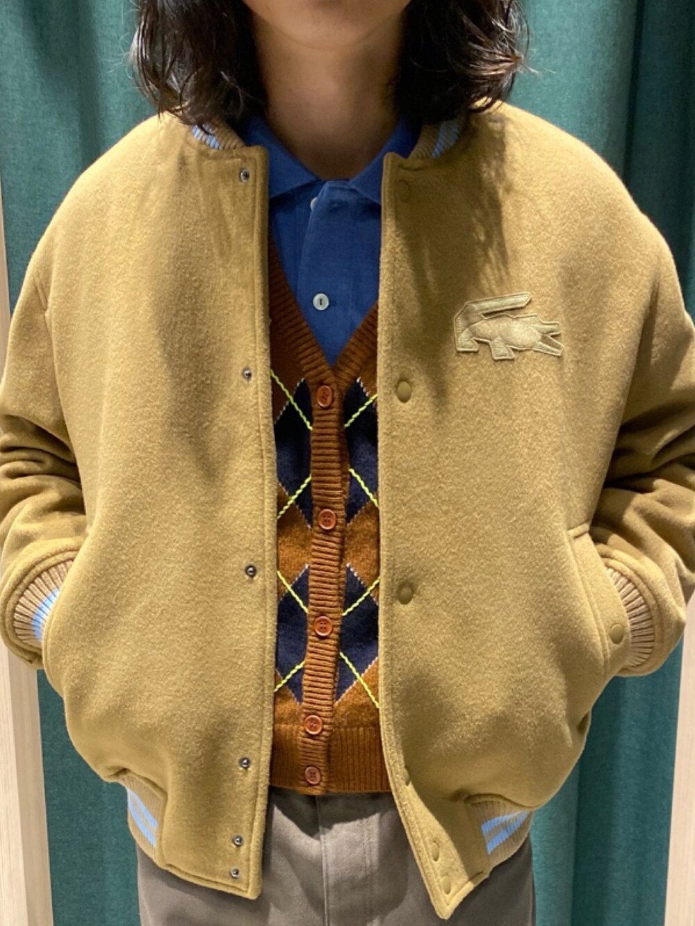 ブルー系のポロシャツ、ブラウン系のブルゾン、ブラウン系のカーディガン/ボレロを着用したメンズの夏コーディネートの2枚目の写真