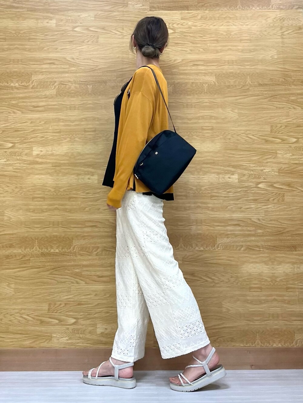 シルバー系のサンダル、イエロー系のカーディガン/ボレロ、ブラック系のTシャツ/カットソーを着用したレディースの春コーディネートの2枚目の写真