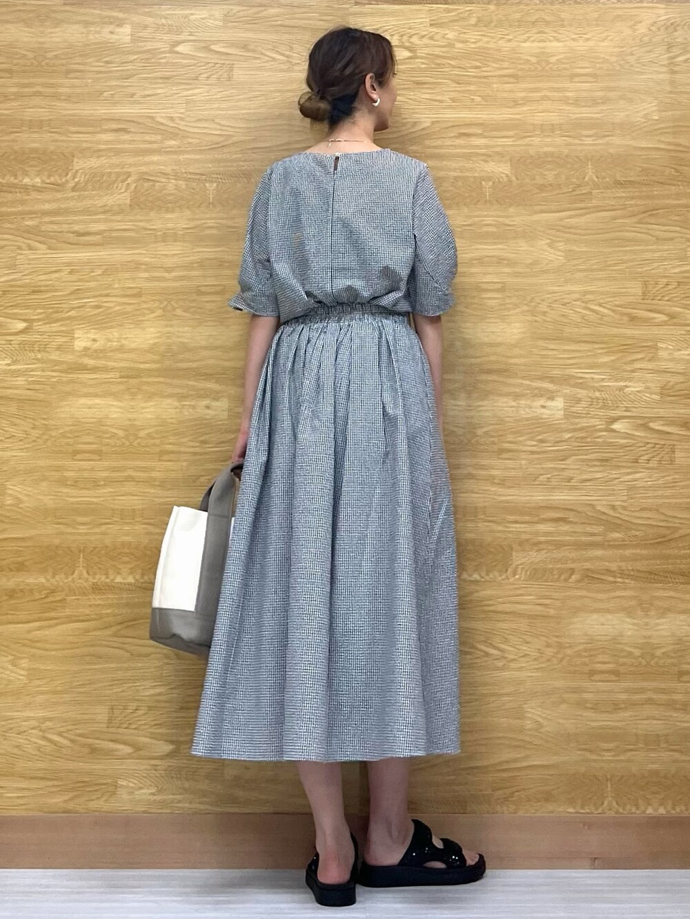 ブラック系のサンダル、ブラック系のスカート、ベージュ系のトートバッグを着用したレディースの春コーディネートの3枚目の写真