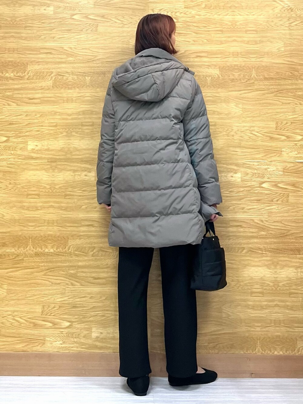 グリーン系のダウンジャケット/コート、レッド系のニット/セーター、ブラック系のトートバッグを着用したレディースの冬コーディネートの3枚目の写真