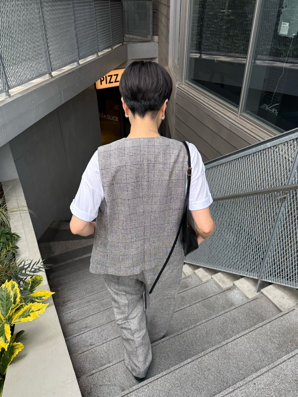 シルバー系のサンダル、ブラック系のショルダーバッグ、グレー系のベストを着用したレディースの夏コーディネートの4枚目の写真