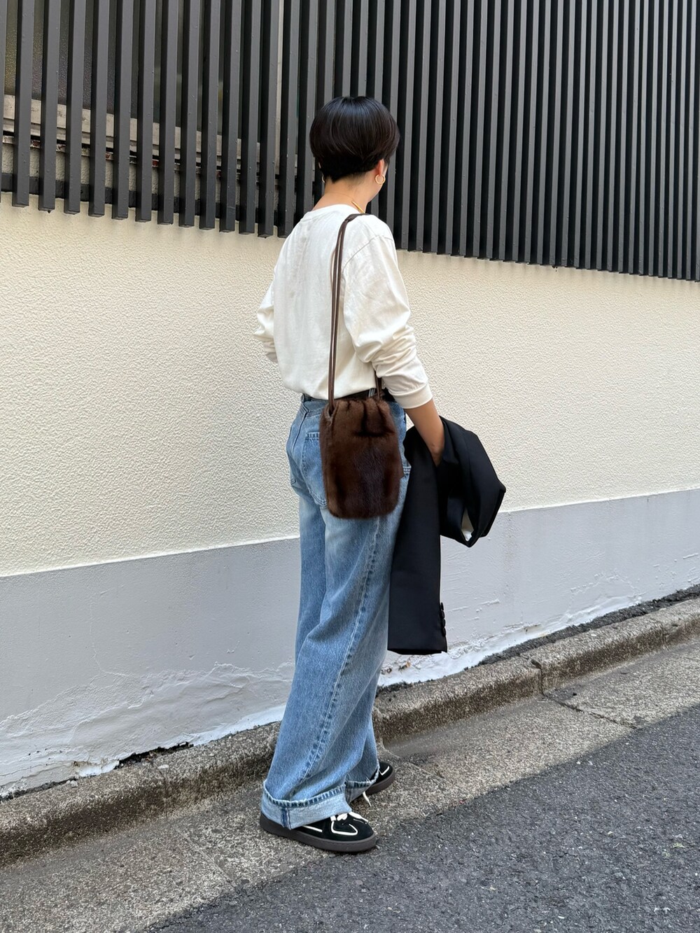 ブラック系のテーラードジャケット、ブルー系のデニムパンツ、ブラック系のスニーカーを着用したレディースの夏コーディネートの6枚目の写真