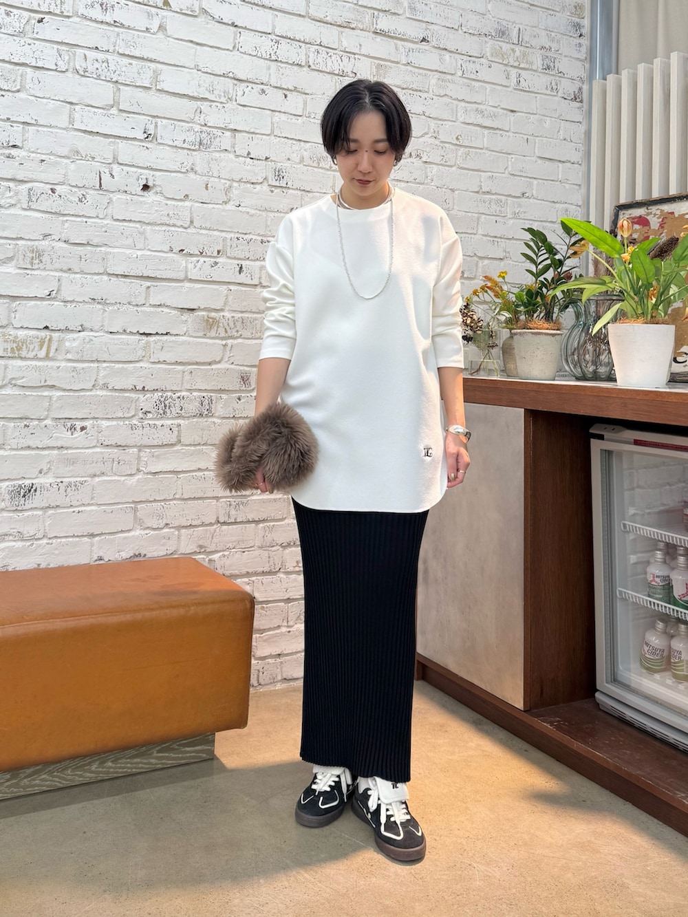 グレー系のチェスターコート、ホワイト系のシャツ/ブラウス、ブラック系のスカートを着用したレディースの秋コーディネートの4枚目の写真