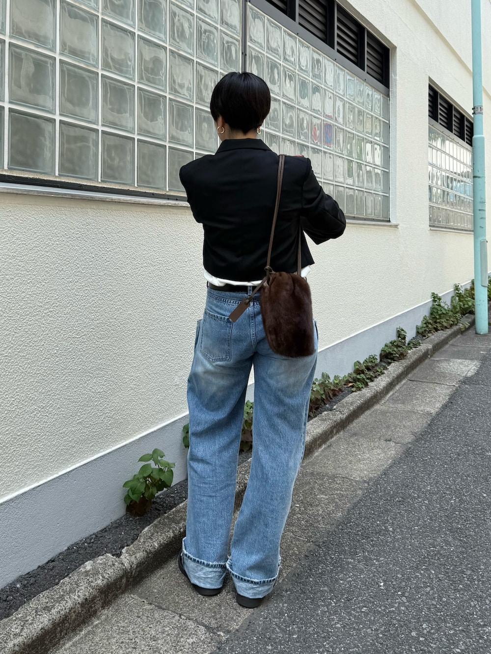 ブラック系のテーラードジャケット、ブルー系のデニムパンツ、ブラック系のスニーカーを着用したレディースの夏コーディネートの2枚目の写真