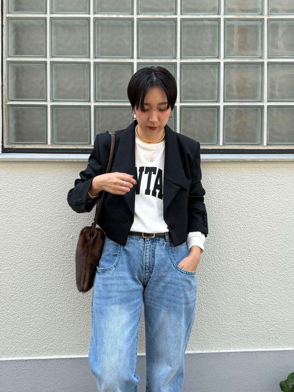 ブラック系のテーラードジャケット、ブルー系のデニムパンツ、ブラック系のスニーカーを着用したレディースの夏コーディネートの3枚目の写真