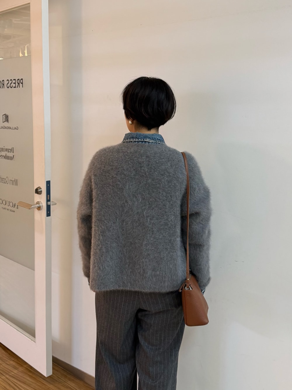 グレー系のカーディガン/ボレロ、ブルー系のデニムジャケット、ブラウン系のパンプスを着用したレディースの秋コーディネートの5枚目の写真