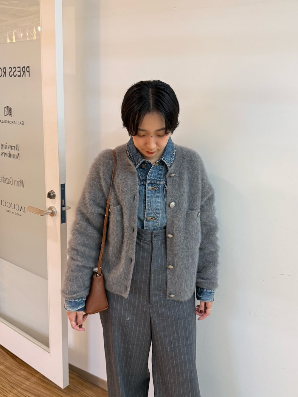 グレー系のカーディガン/ボレロ、ブルー系のデニムジャケット、ブラウン系のパンプスを着用したレディースの秋コーディネートの4枚目の写真