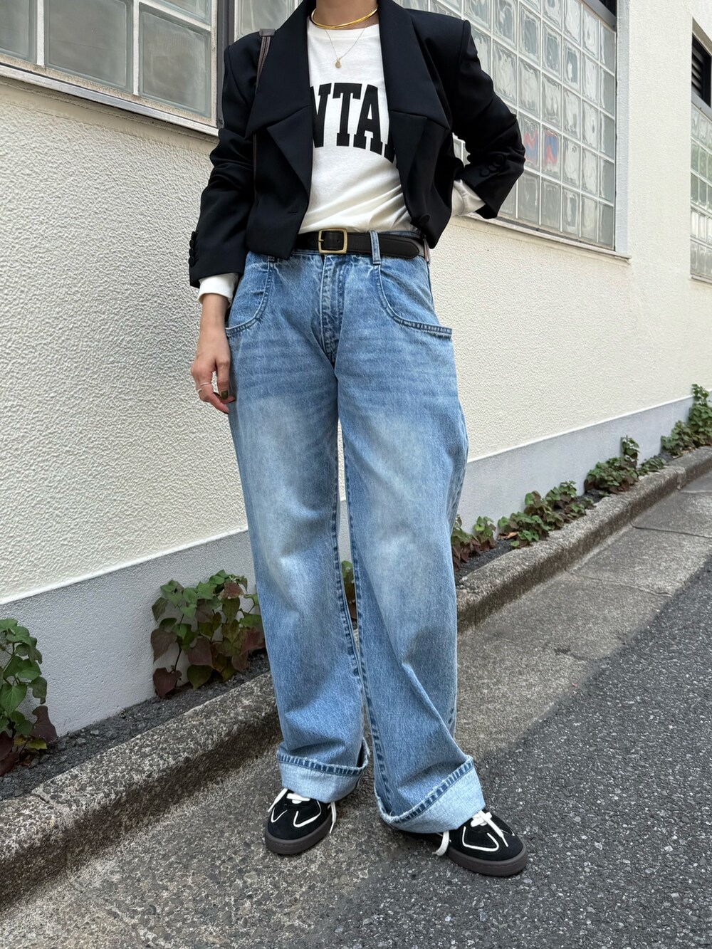 ブラック系のテーラードジャケット、ブルー系のデニムパンツ、ブラック系のスニーカーを着用したレディースの夏コーディネートの4枚目の写真