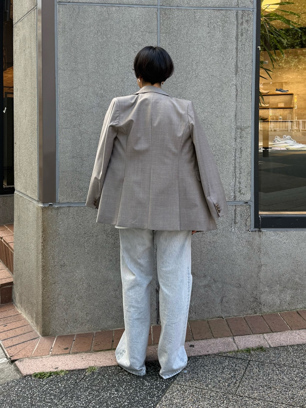 グレー系のテーラードジャケット、ホワイト系のシャツ/ブラウス、グレー系のデニムパンツを着用したレディースの秋コーディネートの3枚目の写真