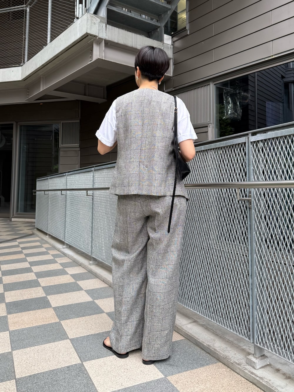 シルバー系のサンダル、ブラック系のショルダーバッグ、グレー系のベストを着用したレディースの夏コーディネートの2枚目の写真