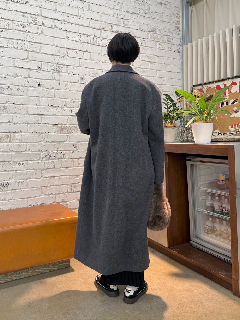 グレー系のチェスターコート、ホワイト系のシャツ/ブラウス、ブラック系のスカートを着用したレディースの秋コーディネートの3枚目の写真