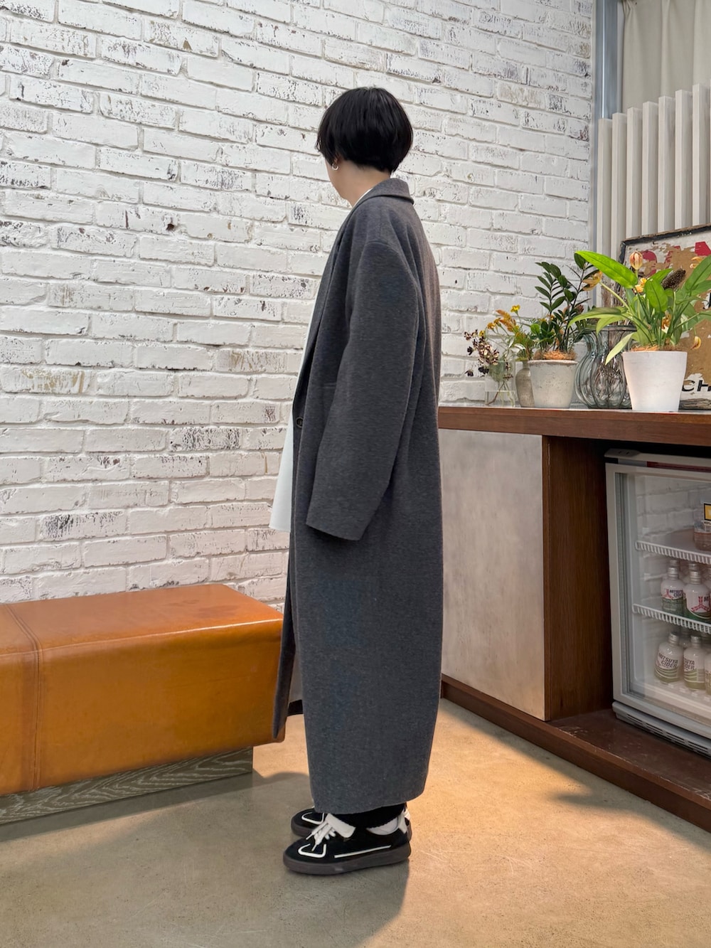 グレー系のチェスターコート、ホワイト系のシャツ/ブラウス、ブラック系のスカートを着用したレディースの秋コーディネートの2枚目の写真