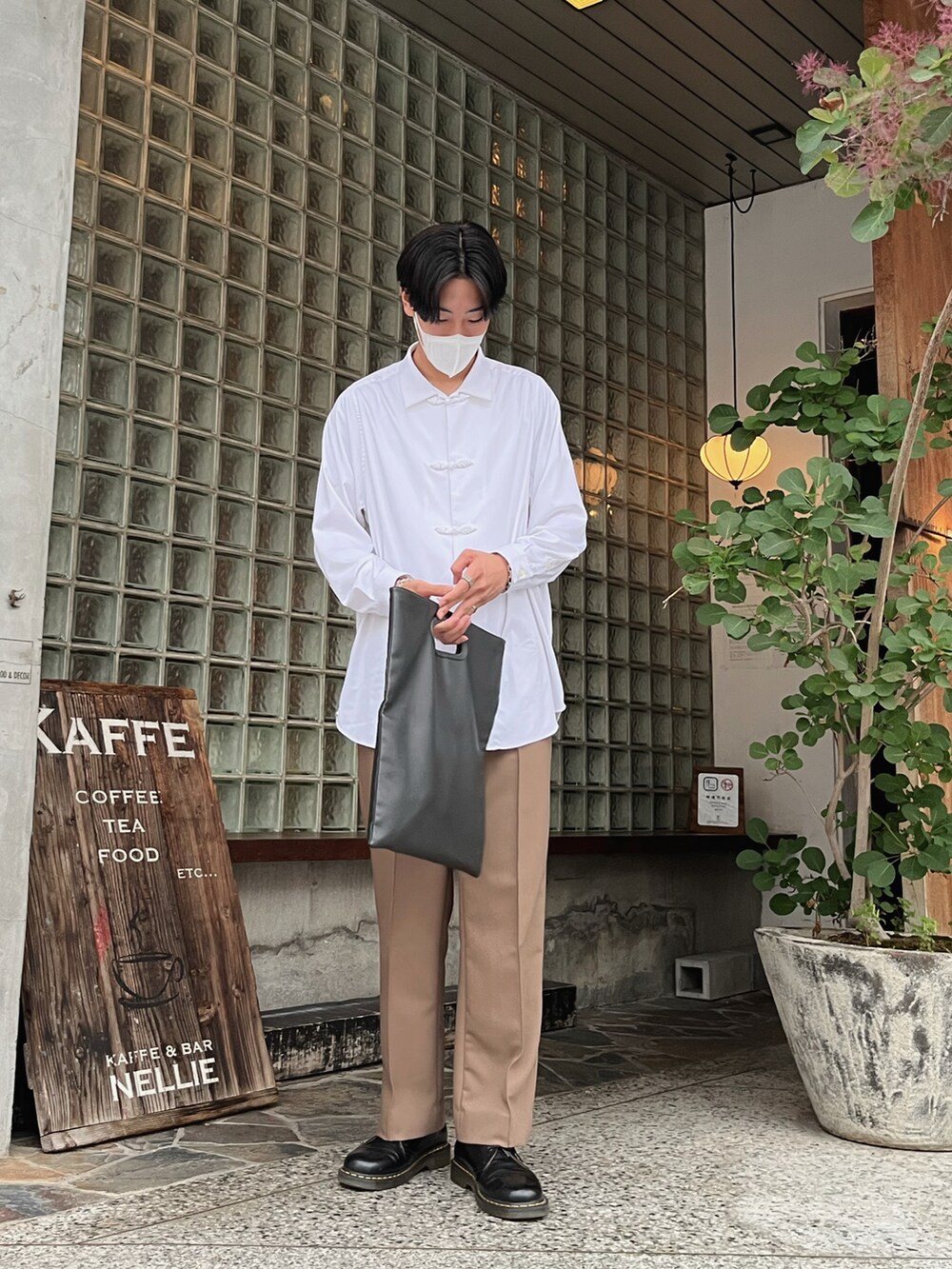 ブラック系のトートバッグ、ベージュ系のスラックス、ブラック系のその他シューズを着用したメンズの秋コーディネートの2枚目の写真