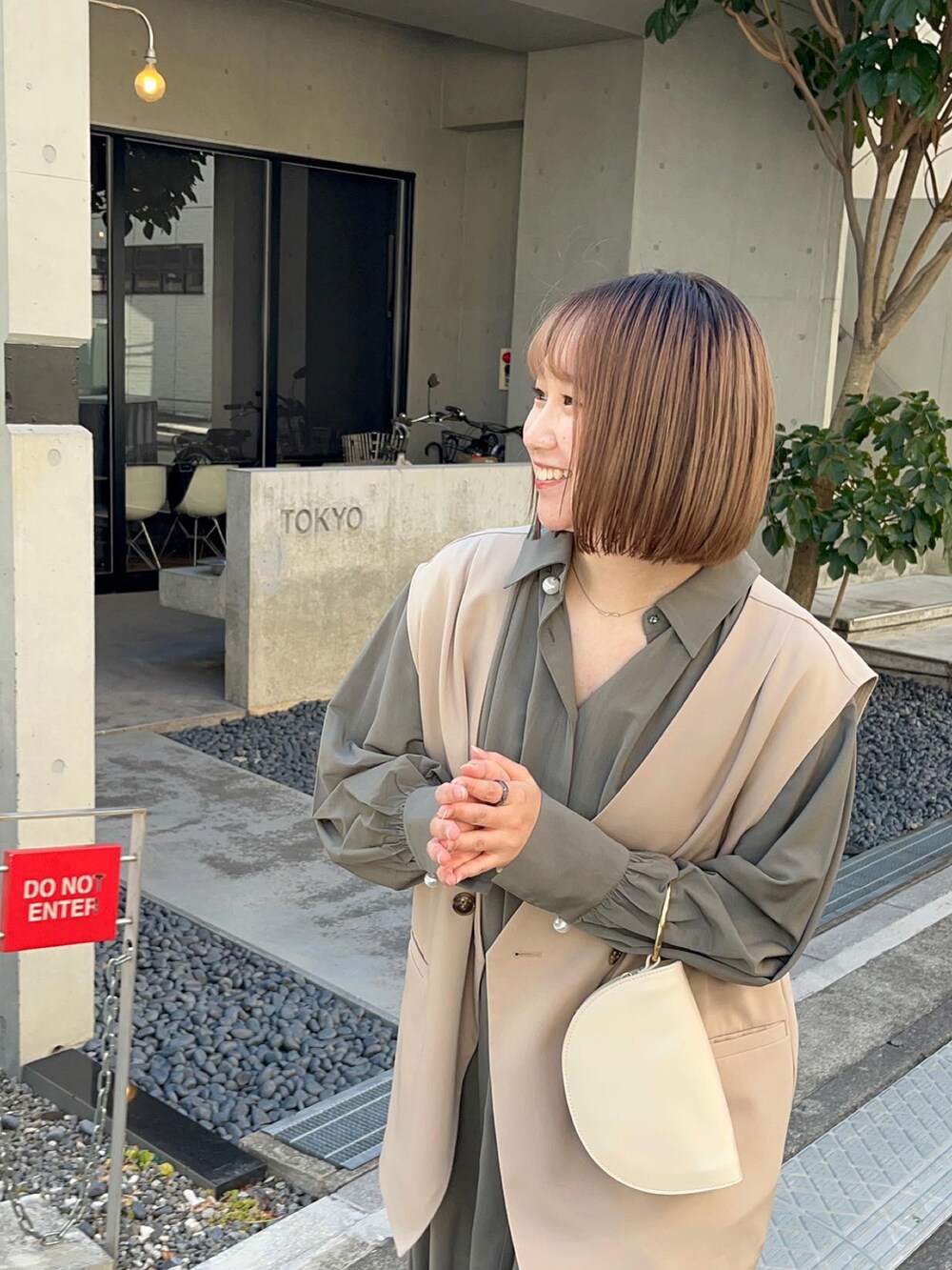 グリーン系のワンピース、ベージュ系のベスト、ホワイト系のハンドバッグを着用したレディースの冬コーディネートの3枚目の写真