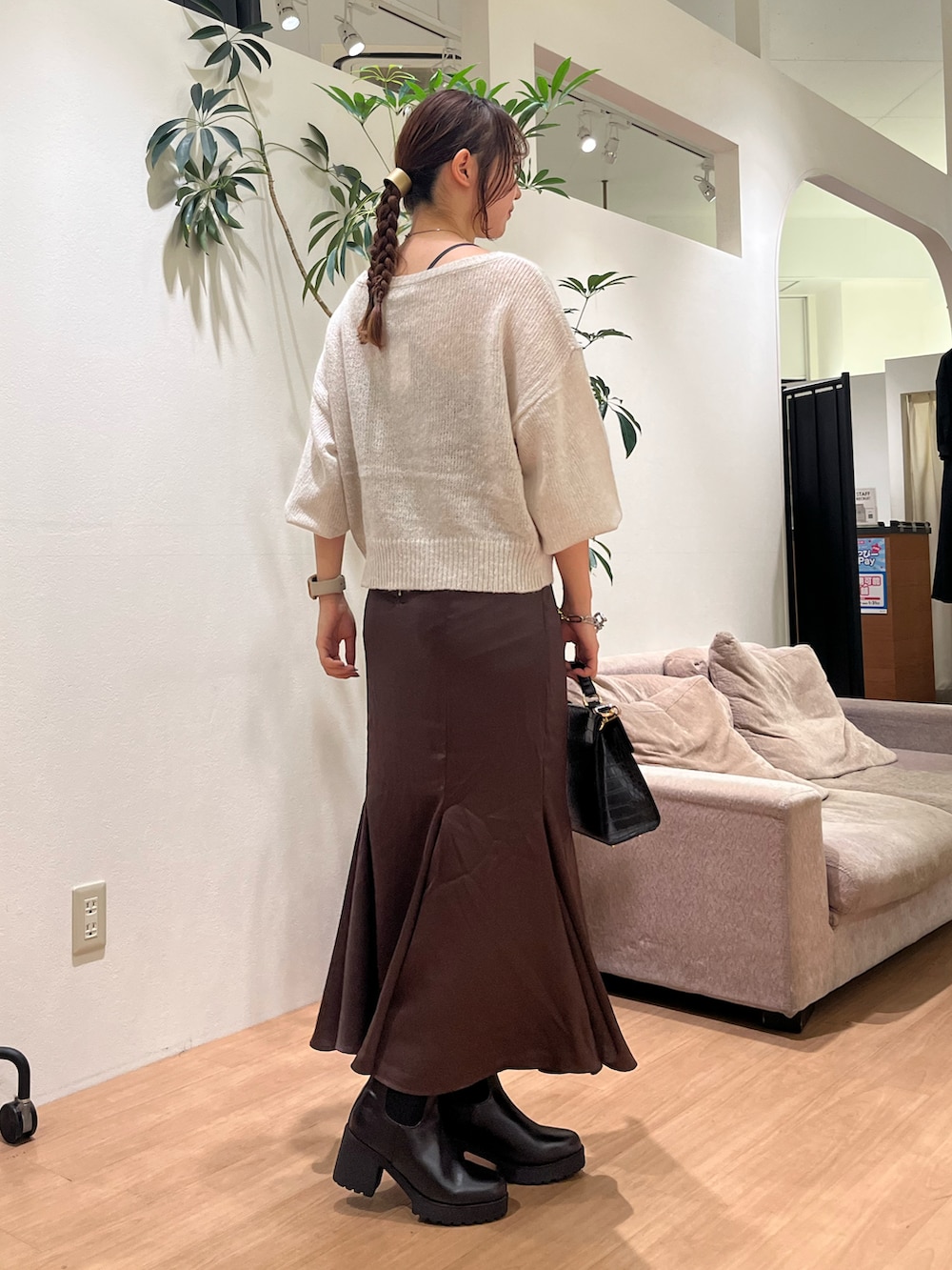 ホワイト系のニット/セーター、ブラウン系のスカート、ブラック系のブーツを着用したレディースの秋コーディネートの2枚目の写真