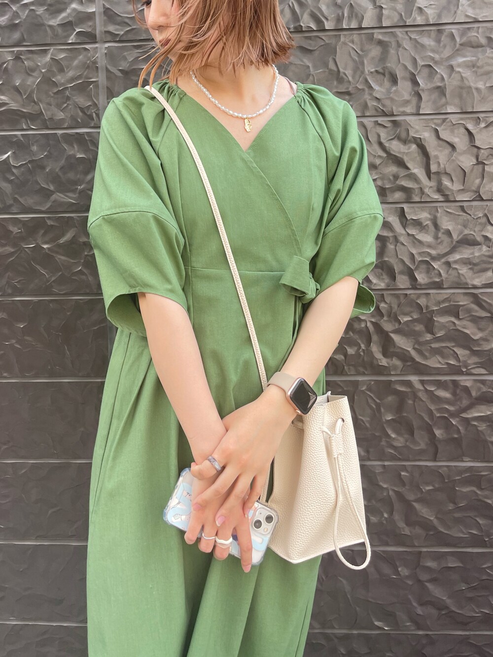 グリーン系のワンピース、ホワイト系のサンダル、ホワイト系のショルダーバッグを着用したレディースの春コーディネートの2枚目の写真